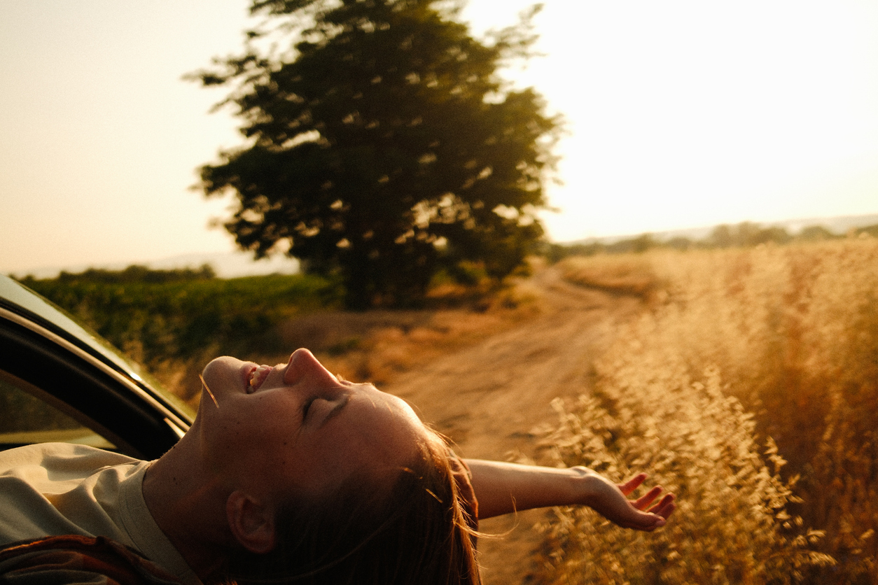 Woman is seen in a good, happy mood, relaxing while hiking or on a travel adventure.
