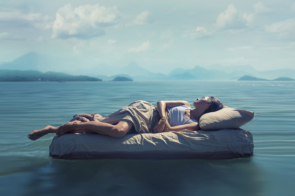 Woman lies on a floating mattress symbolizing deep, restful sleep for blog on CBN oil for sleep.