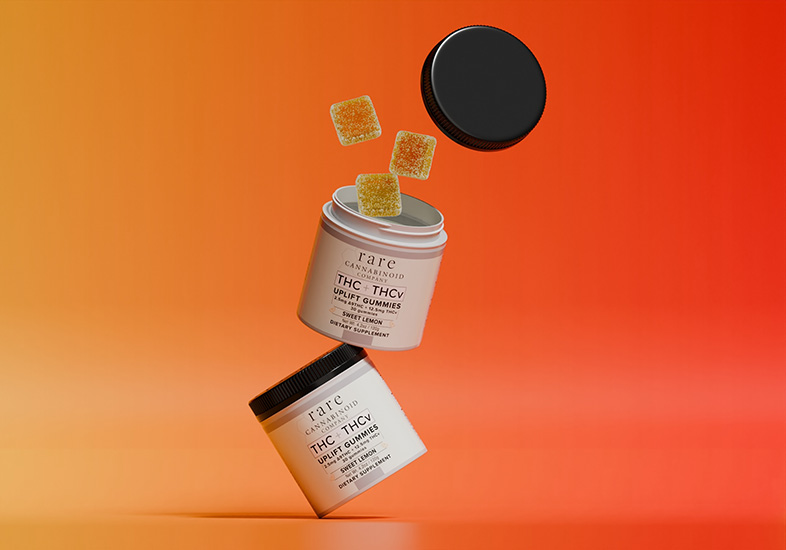 THC THCV Gummies are launched by Rare Cannabinoid Company THC THCV Gummies jars are seen balancing on each other with lemon yellow gummies flying out of the top.