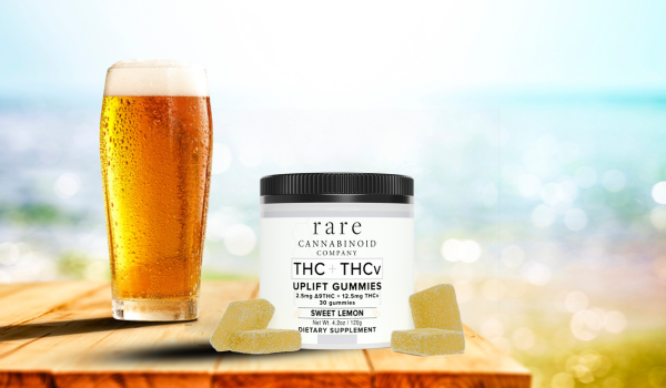 A pint of beer is seen with Rare Cannabinoid Company THC + THCV Uplift Gummies. The beach scene is used for a blog on alcohol and cannabis.